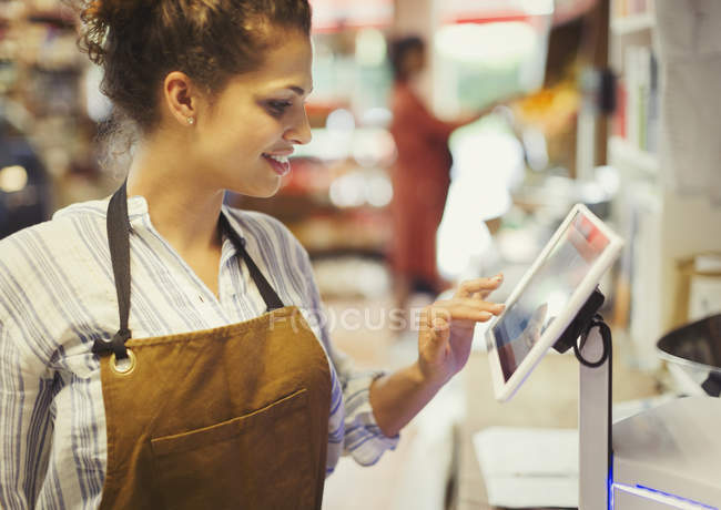 Жіночий касир використовує касовий апарат на сенсорному екрані в продуктовому магазині — стокове фото