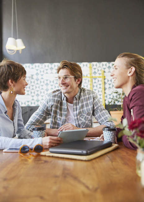 Smiling business people meeting in cafe using digital tablet — Stock Photo