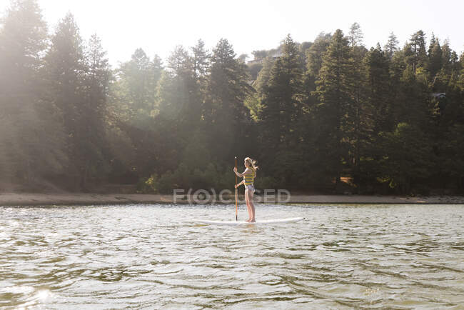 Жінка весло на сонячному, спокійному озері — стокове фото