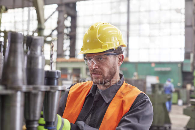 Trabalhador masculino focalizado examinando peças de aço na fábrica — Fotografia de Stock