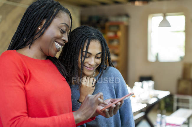 Madre e hija usando un teléfono inteligente - foto de stock