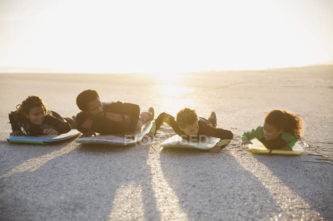 Familia tendida en tablas de surf y boogie boards en la soleada playa de verano - foto de stock