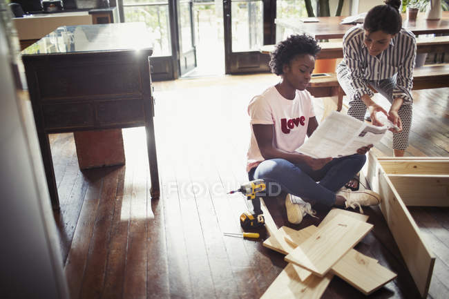 Frauen lesen Anleitungen, bauen Möbel zusammen — Stockfoto