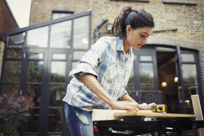 Young woman measuring wood on patio — Stock Photo