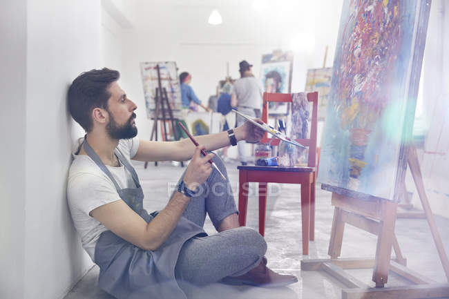 Männlicher Maler, der Malerei im Atelier der Kunstklasse untersucht — Stockfoto