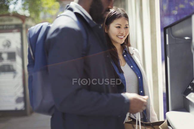 Young couple using ATM on street — Stock Photo