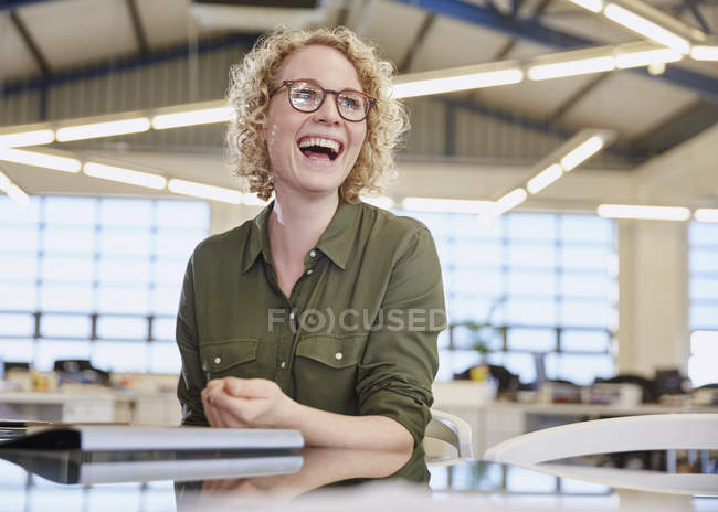 Riéndose mujer de negocios caucásica en la oficina moderna - foto de stock