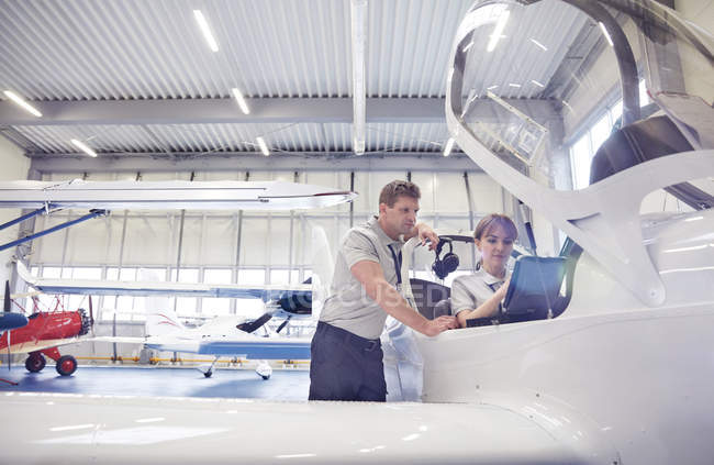 Mechanic engineers working in airplane cockpit in hangar — Stock Photo