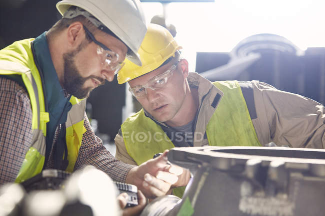 Métallurgistes examinant une pièce d'acier dans une aciérie — Photo de stock
