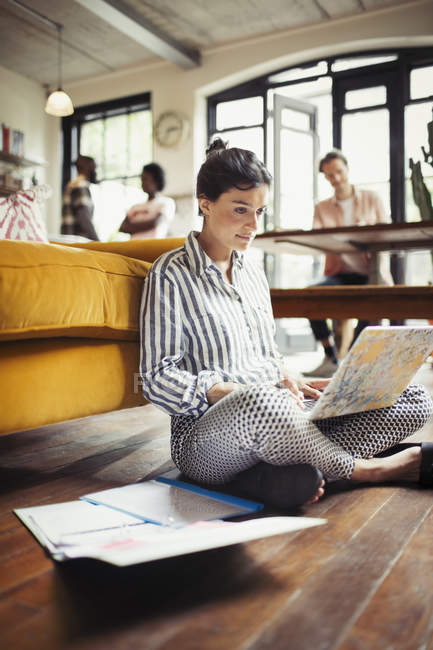 Женщина-фрилансер работает за ноутбуком на полу в гостиной — стоковое фото