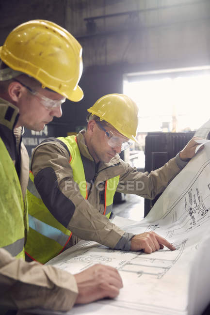 Інженер і сталевий працівник обговорюють креслення в металургійному заводі — стокове фото