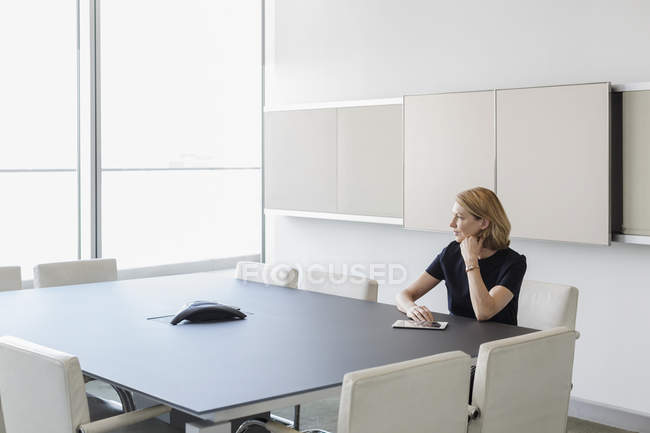Femme d'affaires pensive avec tablette numérique dans la salle de conférence — Photo de stock