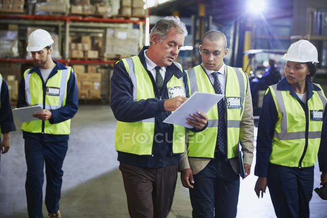 Manger et les travailleurs avec presse-papiers parler dans l'entrepôt de distribution — Photo de stock