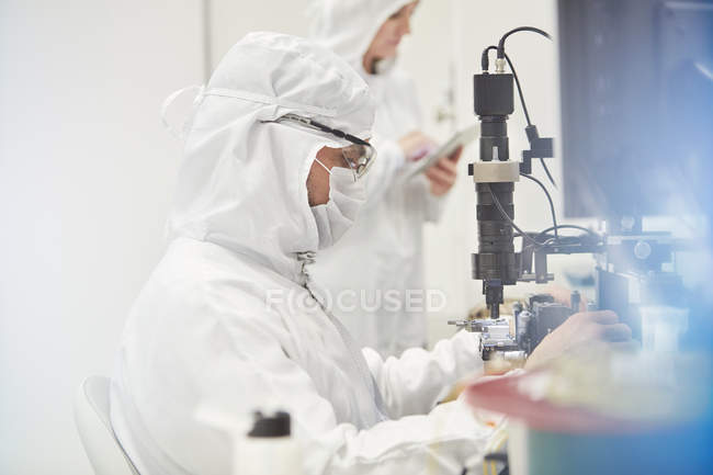 Workers in protective suits using machinery in fiber optics research and testing laboratory — Stock Photo