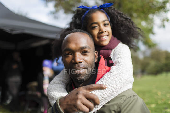 Retrato sonriente padre piggybacking hija en parque - foto de stock