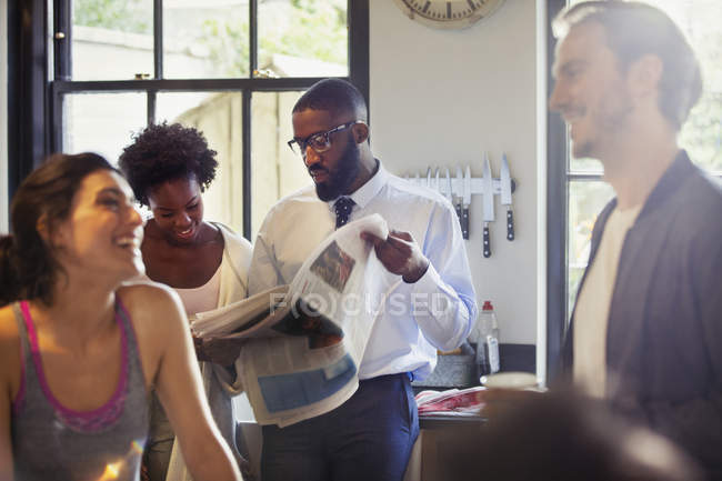 Friend roommates talking and reading newspaper in morning kitchen — Stock Photo