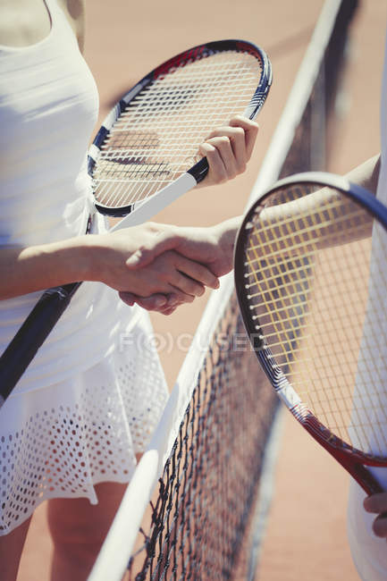 Jogadores de tênis aperto de mão no sportsmanship na net na quadra de tênis ensolarada — Fotografia de Stock