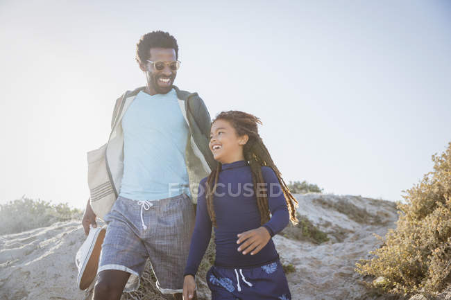 Father and daughter walking on sunny summer beach path — Stock Photo