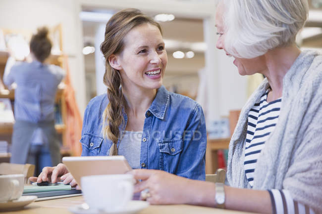 Sorrindo mãe e filha usando tablet digital no café — Fotografia de Stock