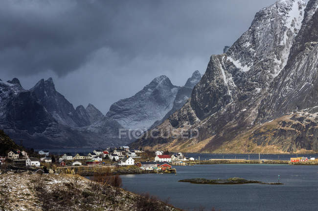 Village de pêcheurs au bord de l'eau sous la neige, montagnes accidentées, Reine, Lofoten, Norvège — Photo de stock