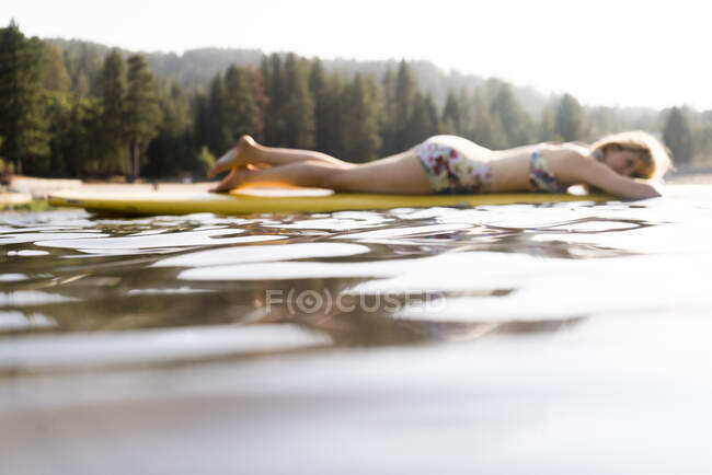 Heitere Frau liegt auf Paddelbrett auf ruhigem See — Stockfoto