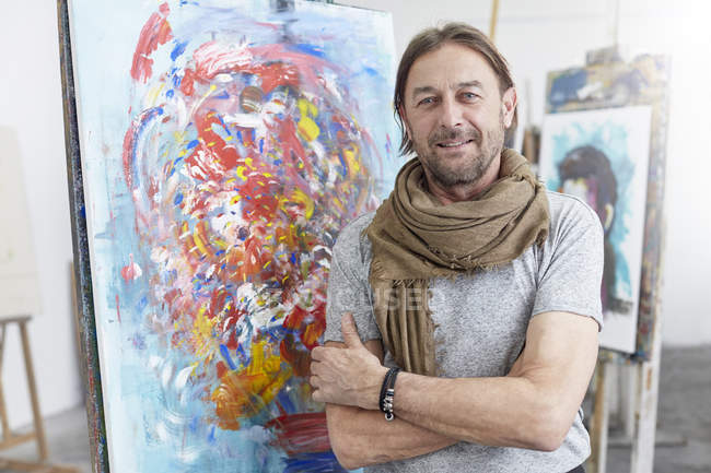 Portrait souriant, artiste confiant debout à la peinture abstraite en atelier de classe d'art — Photo de stock