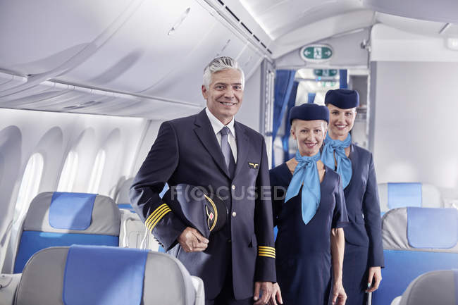 Портрет уверенный пилот и стюардессы на самолете — стоковое фото