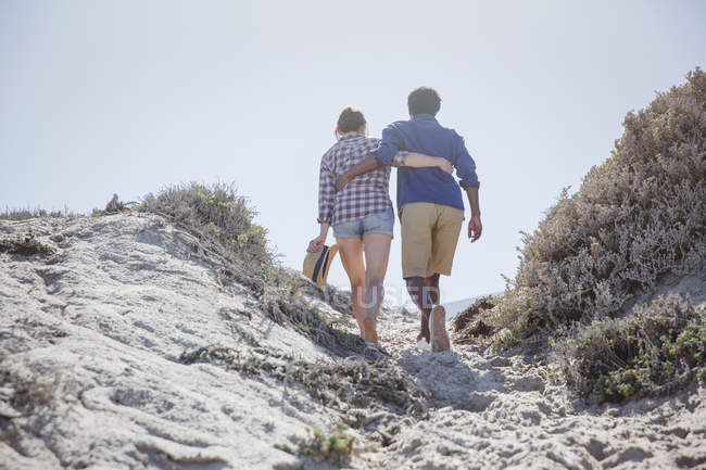 Ласковая пара, идущая по песчаной солнечной летней пляжной дорожке — стоковое фото