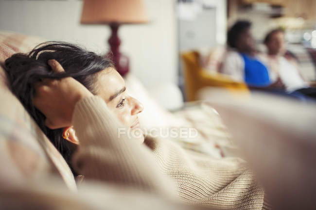 Junge Frau entspannt mit der Hand im Haar auf dem Sofa — Stockfoto