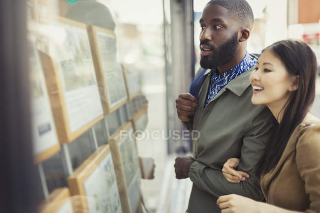 Casal jovem navegando anúncios imobiliários na loja — Fotografia de Stock