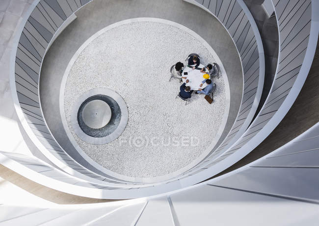 Blick von oben Geschäftsleute treffen sich am Tisch im runden, modernen Atriumhof — Stockfoto