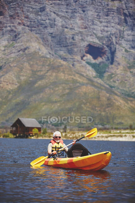 Hombre mayor activo kayak en el soleado lago de verano - foto de stock