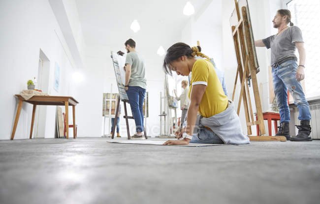 Женщина-художник рисует на полу в студии художественного класса — стоковое фото