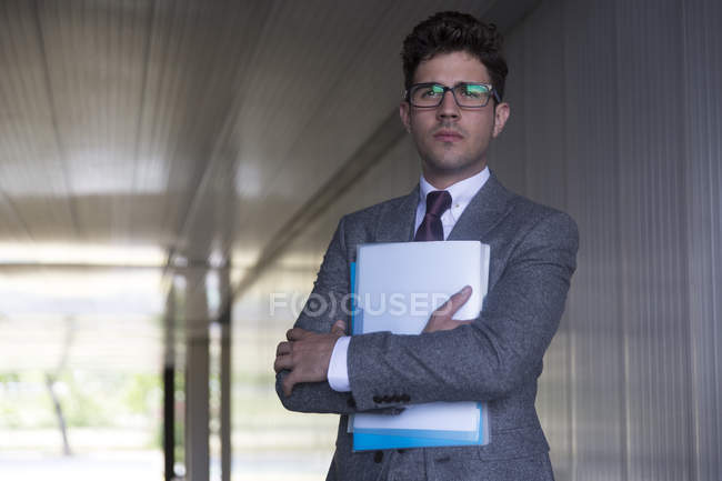 Portrait serious businessman holding paperwork in office corridor — Stock Photo