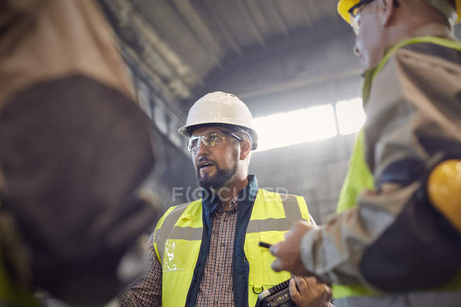 Supervisor talking to steelworkers in steel mill — Stock Photo