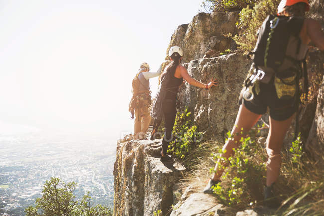 Alpinistas escalando rochas acima do oceano ensolarado — Fotografia de Stock