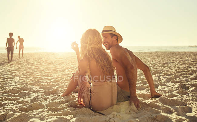 Pareja joven relajándose en la soleada playa de verano - foto de stock