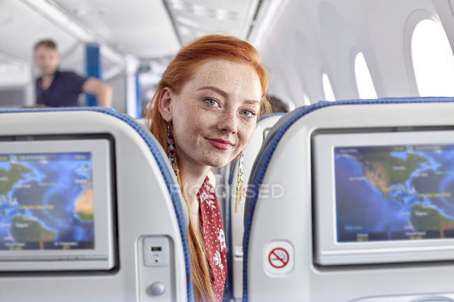 Portrait smiling young woman with red hair and freckles on airplane — Stock Photo
