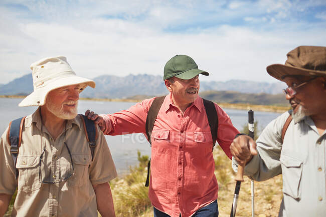 Hommes âgés actifs amis randonnée au bord du lac ensoleillé — Photo de stock