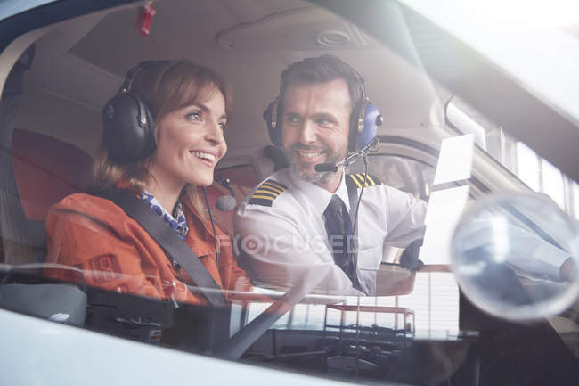 Pilot talking to smiling in passenger in airplane cockpit — Stock Photo