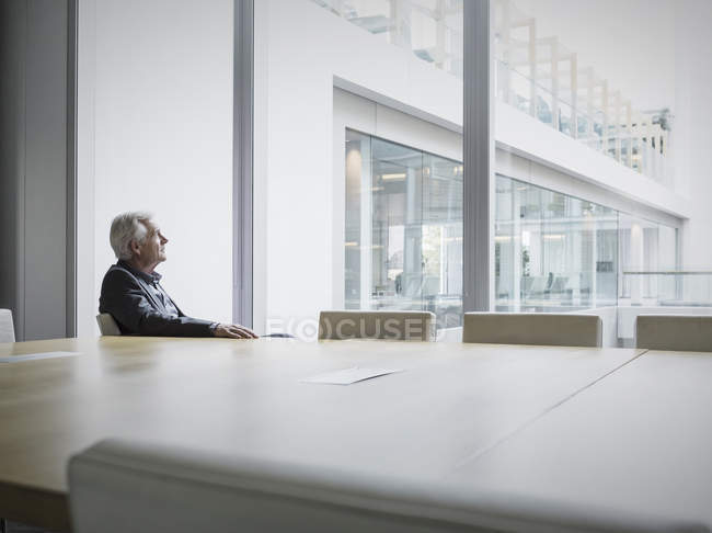 Uomo d'affari anziano pensieroso che guarda fuori dalla finestra della sala conferenze — Foto stock