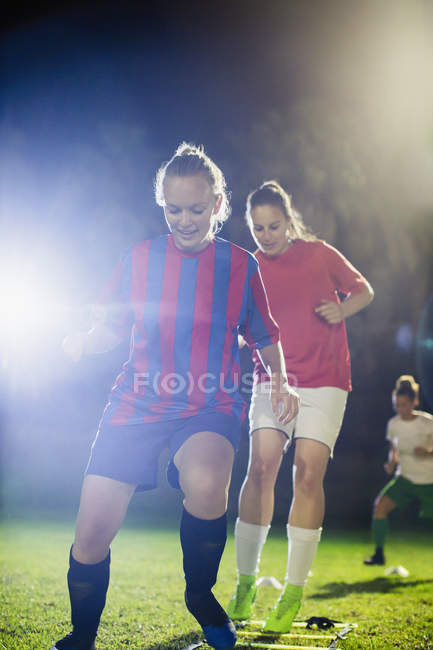 Jóvenes futbolistas practicando deportes de agilidad en el campo por la noche - foto de stock