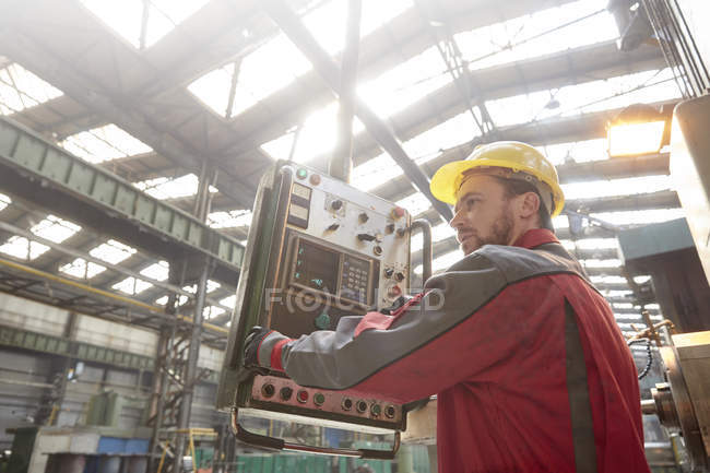 Männlicher Arbeiter, der Maschinen am Schaltschrank in der Fabrik bedient — Stockfoto