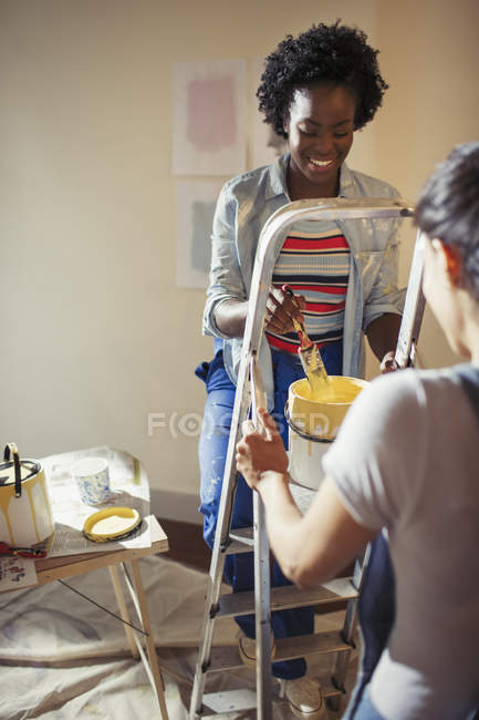 Women with yellow paint painting living room — Stock Photo