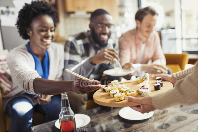 Amici che mangiano sushi in salotto — Foto stock