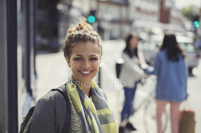 Portrait smiling young woman on sunny urban street — Stock Photo