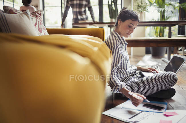 Женщина-фрилансер работает за ноутбуком на полу в гостиной — стоковое фото