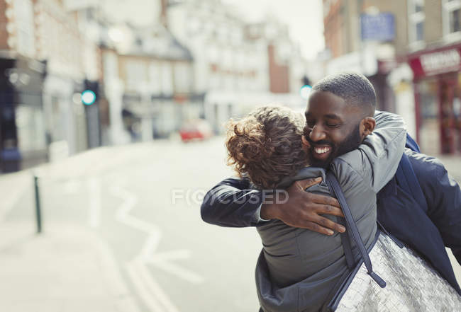 Glückliches, anhängliches junges Paar, das sich auf der sonnigen Stadtstraße umarmt — Stockfoto