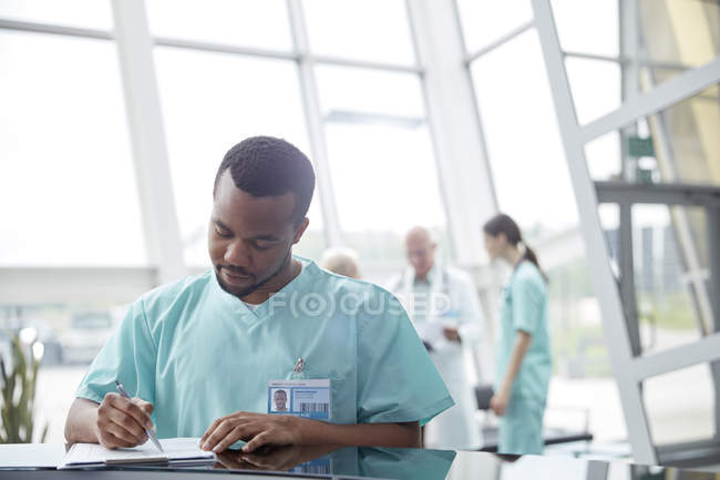 Чоловіча медсестра розглядає медичний запис у вестибюлі лікарні — стокове фото