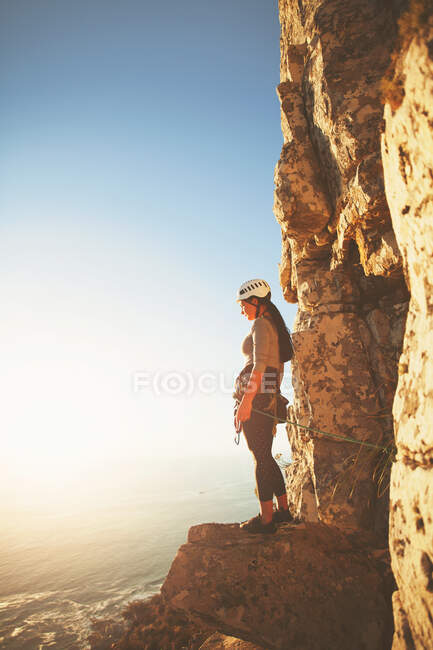 Mulher alpinista olhando para a vista ensolarada do oceano — Fotografia de Stock